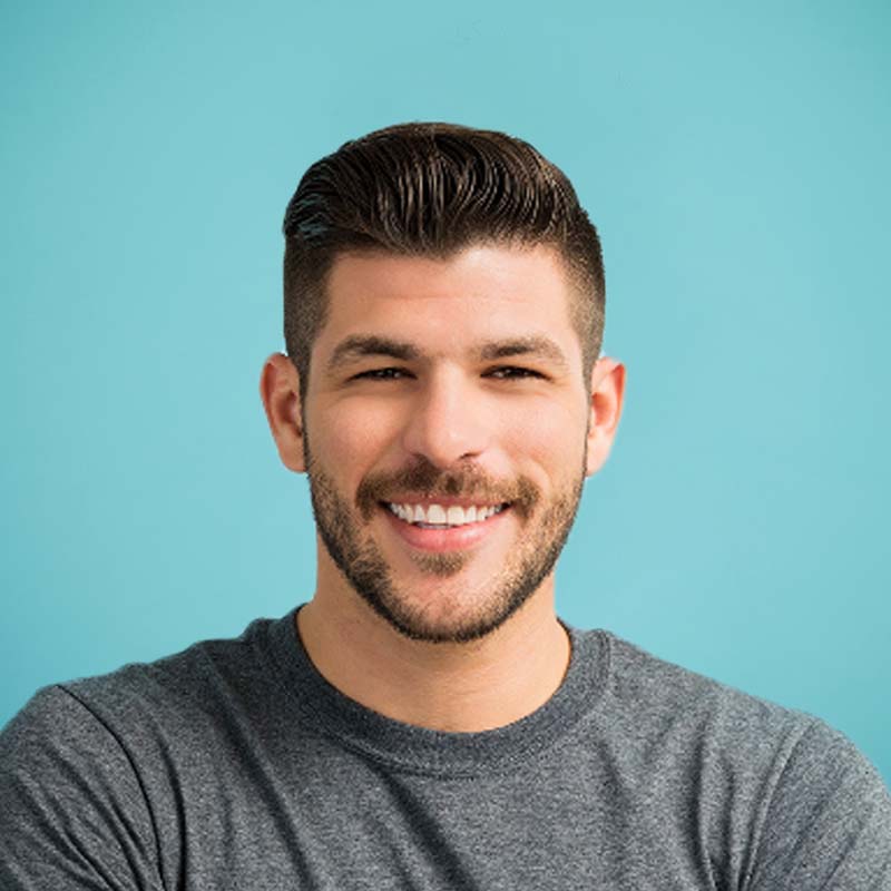 dark haired male smiling against blue backdrop