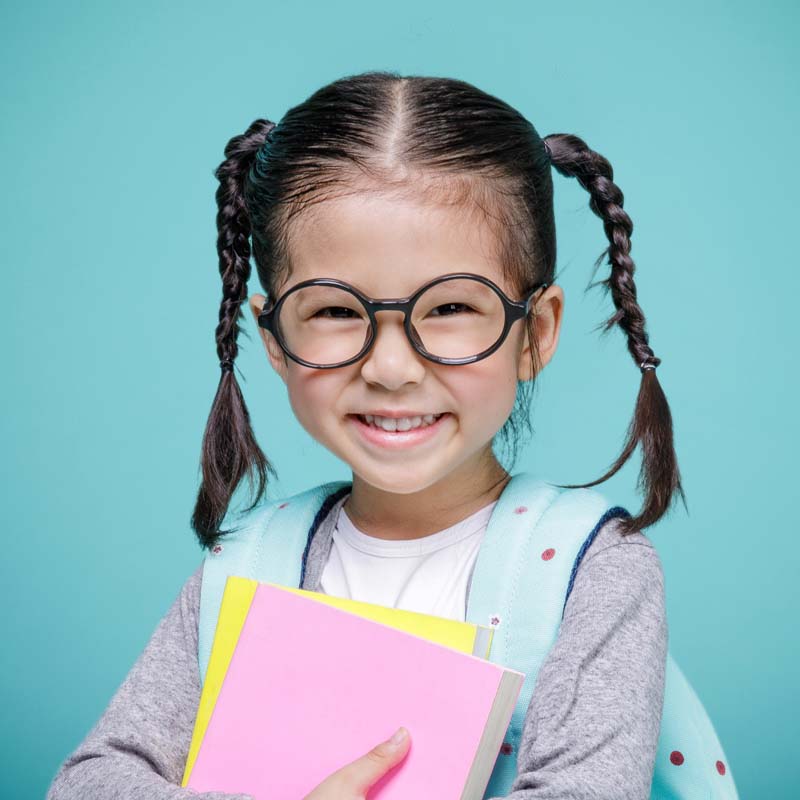 adorable little girl with glasses and braids smiling