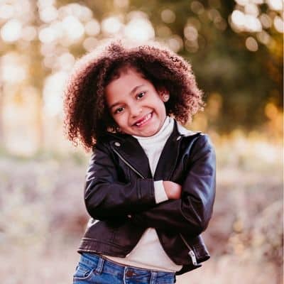 Cute little girl with crossed arms smiling and posing
