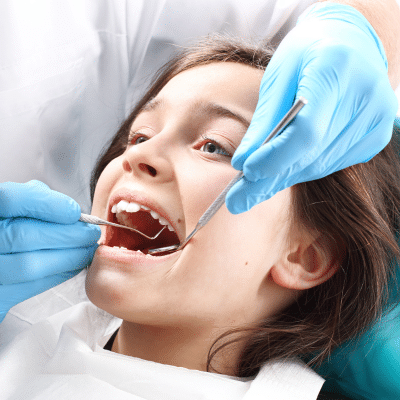 Little kid getting teeth worked on by a dentist, representing dental sealants