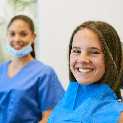 A little girl smiling at the dentist, representing regular dental checkups and cleanings