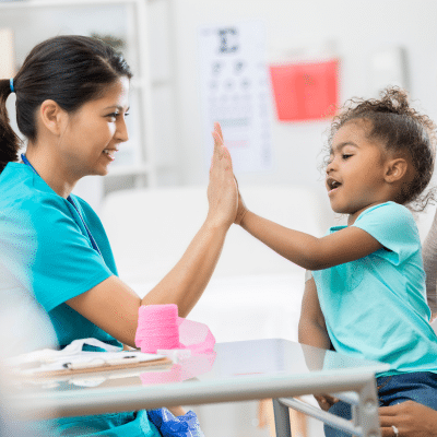 A female pediatric dentist giving a high five to a child, representing pediatric dentist in santa clarita