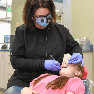 Dr. Kathleen mulcahey at valencia smiles orthodontics & pediatric dentistry, works on little girl's teeth, representing orthodontic treatment in valencia ca