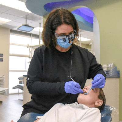 Dr. Kathleen mulcahey working on a little kid's teeth, representing what to do if your child knocks out a tooth